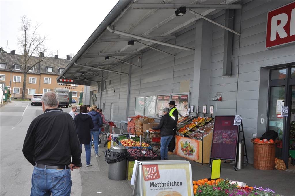 Rewe-Türsteher möchte seinen Kunden einfach „Danke!“ sagen Die Kunden vom Rewe-Markt in Dortmund-Dorstfeld warten auf Einkaufswagen, um den Laden betreten zu dürfen.