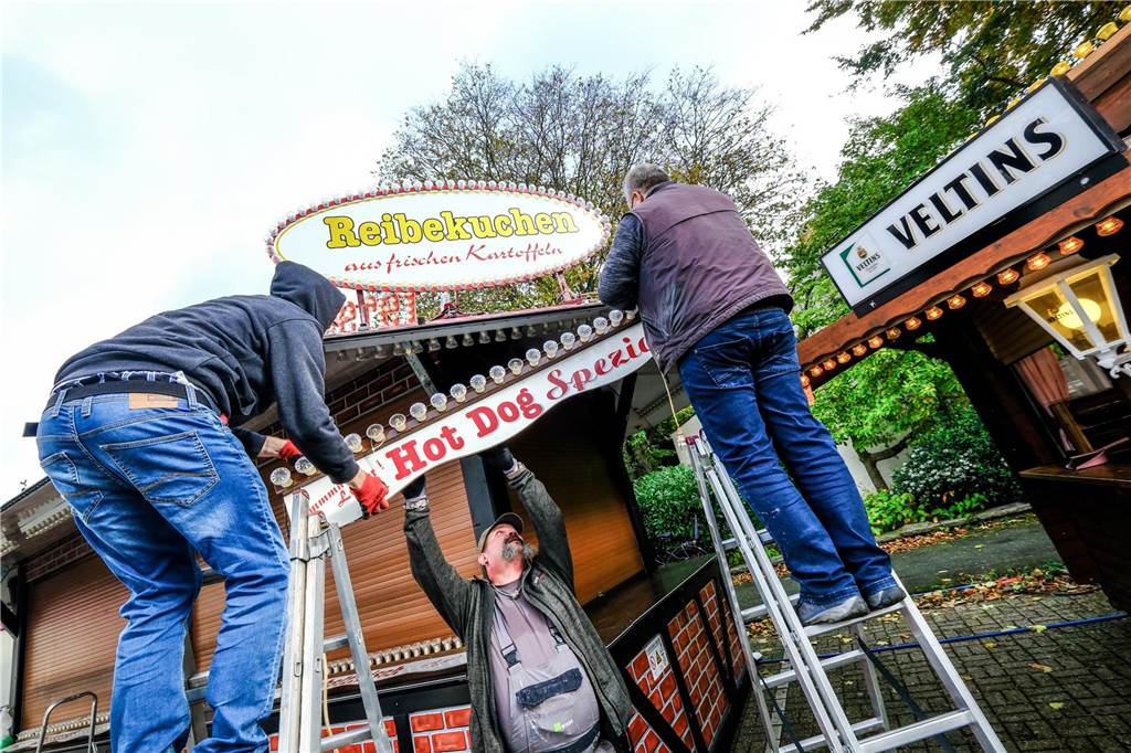 „Recklinghausen leuchtet auch in Süd“: Allerheiligenkirmes 2023 startet Drei Schausteller werkeln an ihrer Bude auf der Allerheiligenkirmes in Recklinghausen-Süd