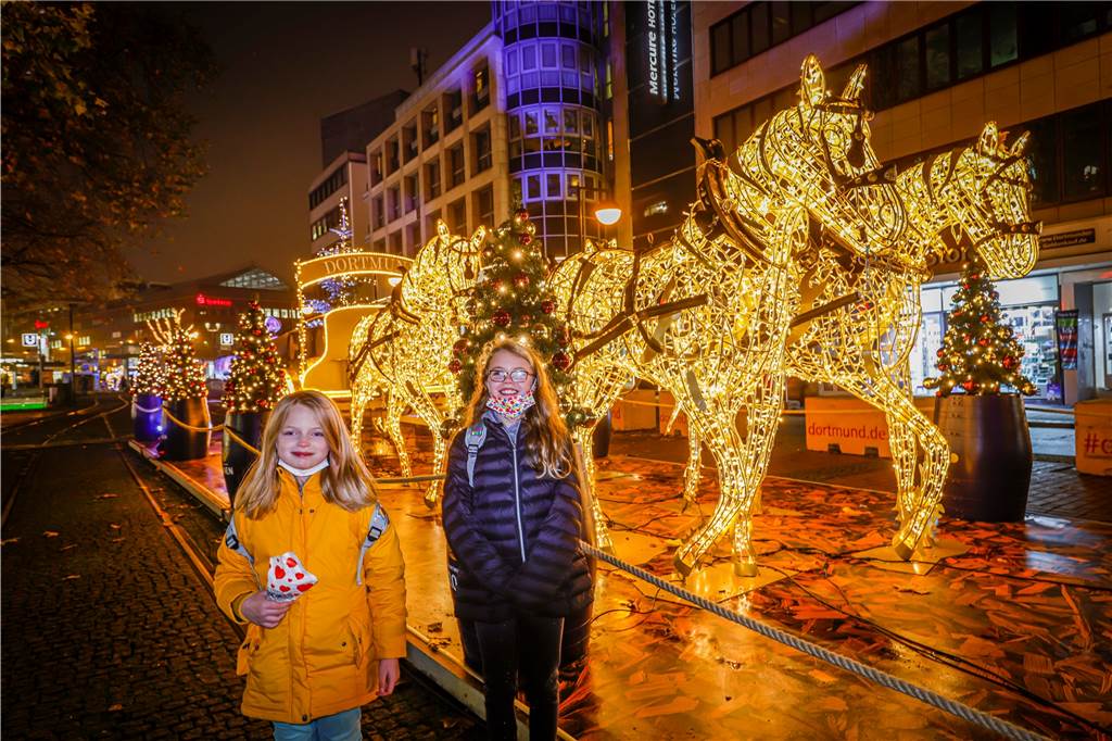 Zwei Mädchen stehen beim Weihnachtsmarkt in Dortmund vor einer Lichtskulptur auf der Kampstraße.
