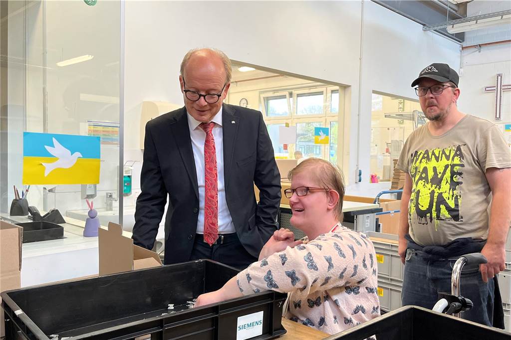 Beschäftigte präsentiert ihre Arbeit den Gästen. Sie sortiert an diesem Nachmittag Metallteile in kleinere Kisten.