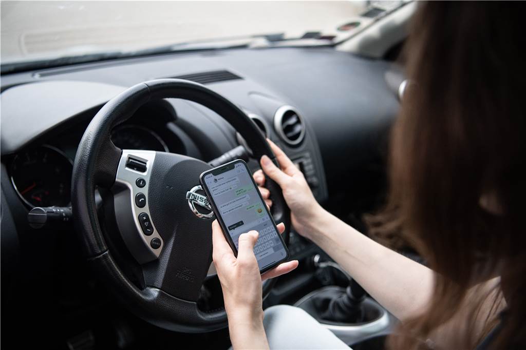 Bußgeldkatalog für Autofahrer: In diesen 10 Fällen zahlt man am meisten Eine Frau sitzt mit Handy am Steuer