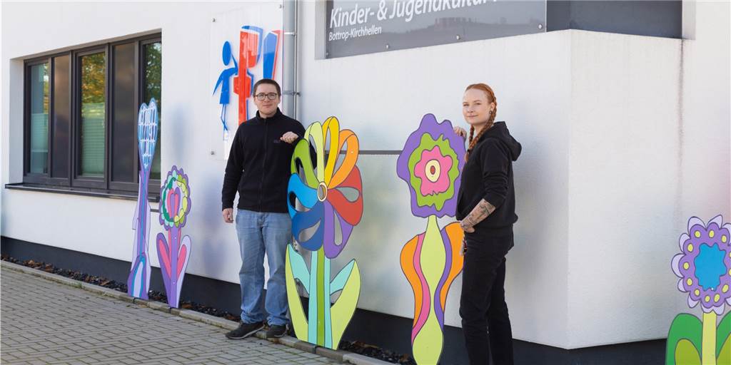 Jugendhaus f! zeigt: „Wir sind kunterbunt und vielfältig“ Menschen stehen neben Kunstblumen
