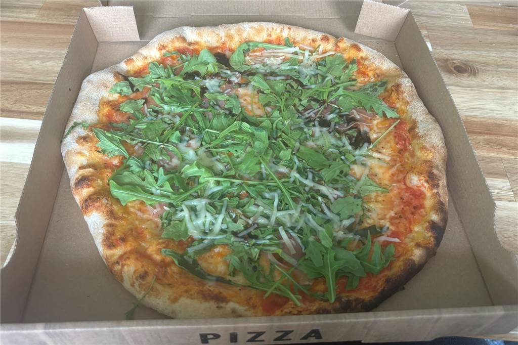 Zwischen Pizza und indischen Speisen: Il Rustico überzeugt im Test Eine Pizza mit Rucola und Parmaschinken liegt in einem Pizzakarton.