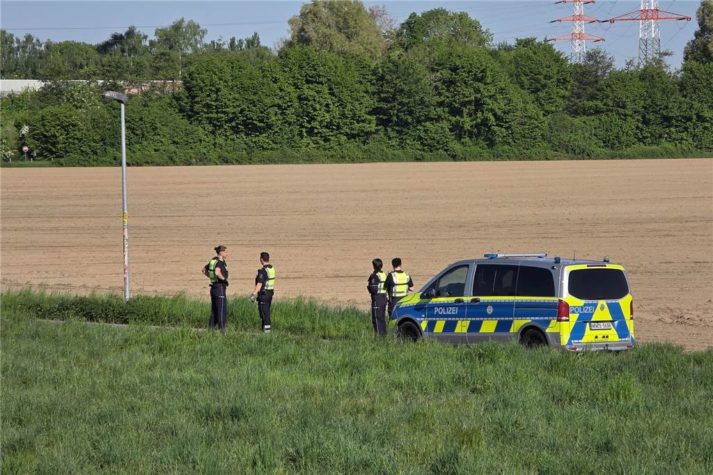 Vier Polizeibeamte stehen an einem Polizeiwagen. 
