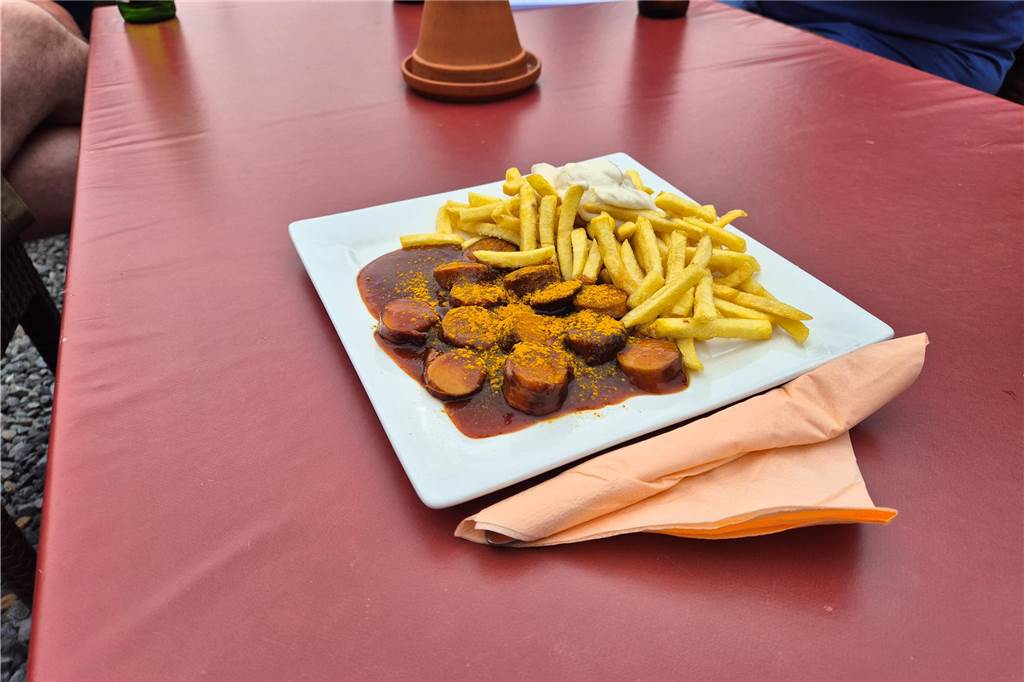 Mit Blick auf die Ruhr: Naturbiergarten „Zur Lennemündung“ im Check Ein Teller mit Currywurst und Pommes steht auf einem Tisch.