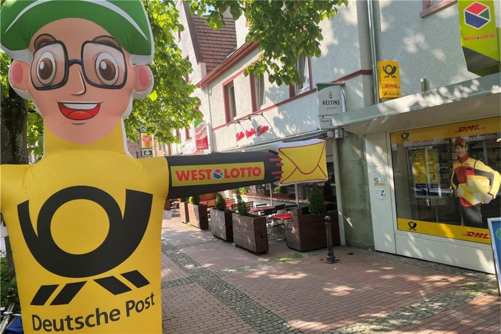 Keine VRR-Tickets in Haltern erhältlich: Service-Bus fehlt seit Wochen Werbefigur der Deutschen Post steht auf einer Einkaufsstraße vor einer Postfiliale.