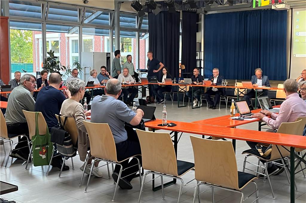 Menschen sitzen in einem Kreis an Tischen in einem großen Raum.