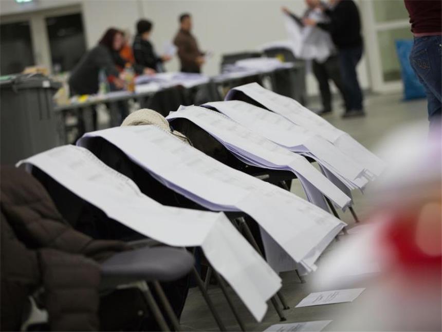 Die riesigen Wahlscheine der Frankfurter Briefwähler werden in der Messehalle 10 auf Stullehnen zwischengeparkt, während zahlreiche Wahlhelfer die Scheine entfalten. Foto: Frank Rumpenhorst