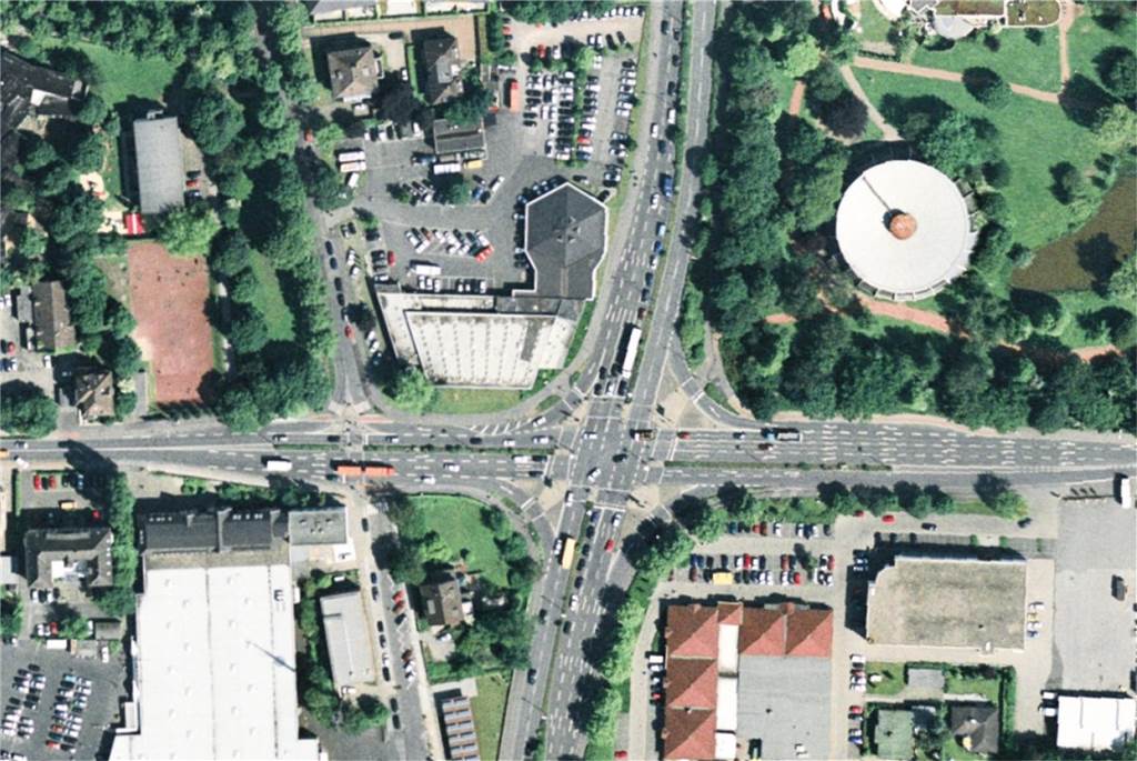 Das Luftbild um die Jahrtausendwende herum, unterscheidet sich kaum von dem aus 2023. Die Turnhalle steht, die Kreuzung ist stark befahren. 