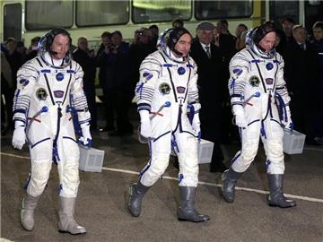 Die Russen Alexander Skworzow (M) und Oleg Artemjew (r) sowie der US-Amerikaner Steve Swanson auf dem Weg zur Sojus-Rakete. Foto: Maxim Shipenkov