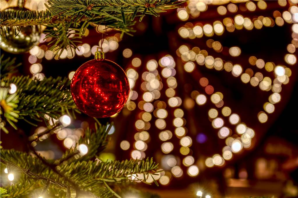 Zu sehen ist die hell erleuchtete Seilscheibe auf der Wiese am Ickerner Knoten. Im Vordergrund sind Tannenäste und eine Christbaumkugel abgebildet.