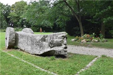 Die Skulptur "WOZ" ziert den Eingang, rechts ein erst vor wenigen Jahren angelegtes Blumenbeet.