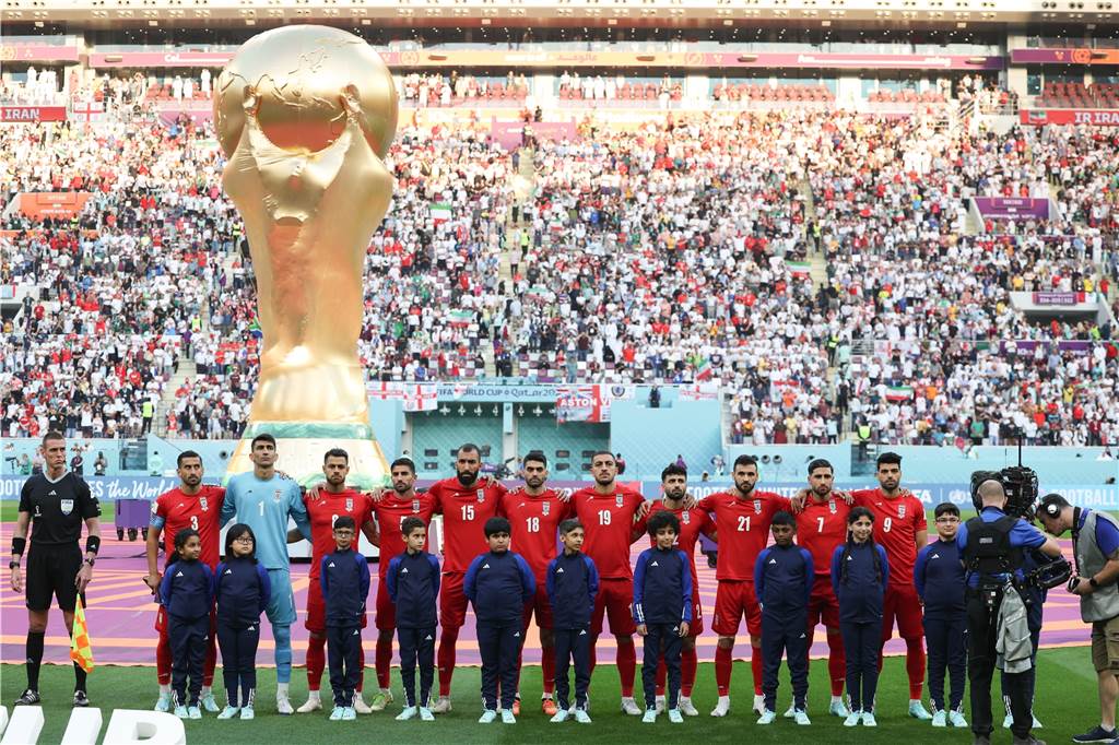 Spieler des Iran stehen bei der Nationalhymne vor dem übergroßen Weltpokal