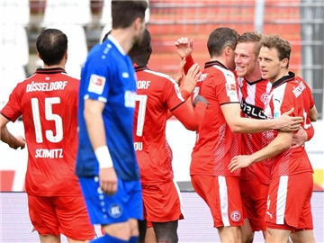 Die Spieler von Fortuna Düsseldorf feiern hinter einem Spieler des Karlsruher SC das 2:0. Foto: Uwe Anspach