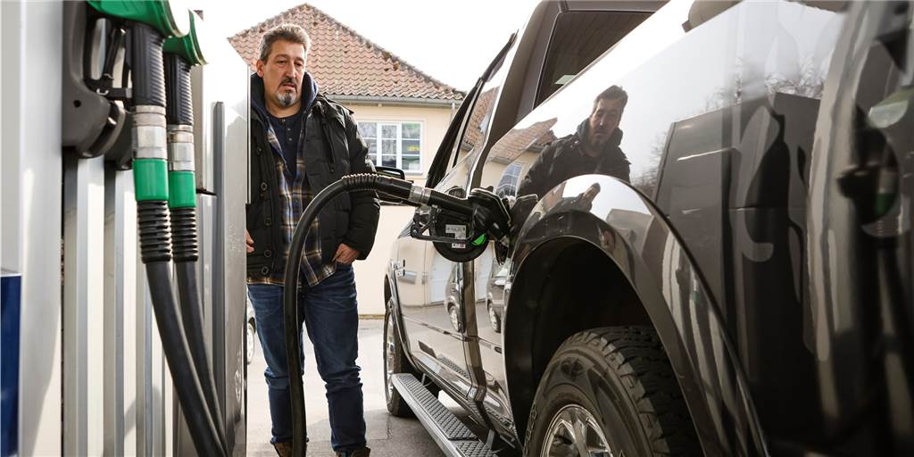Höhere Gewinne durch den Tankrabatt: Kartellamt nimmt Ölkonzerne ins Visier Ein Mann steht neben seinem Auto, während es volltankt.