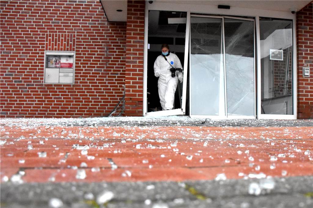 Riesiger Schaden: Gewaltige Explosion zerstört Sparkassen-Foyer Eine Mitarbeiterin der Spurensicherung der Kriminalpolizei verlässt das zerstörte Sparkassen-Foyer. Glassplitter haben sich im weiten Umkreis verteilt.