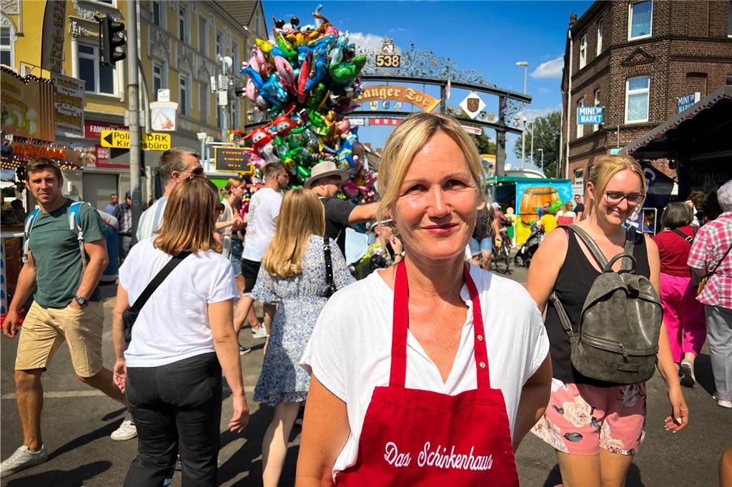 Vor Start der Cranger Kirmes: Daniela Miske kündigt neues Projekt an Eine Frau mit weißem T-Shirt und roter Schürze steht in einer Menschenmenge.