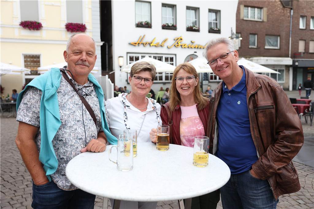 Ein paar Besucher des Festes stehen an einem Tisch und lächeln in die Kamera. Auf dem Tisch steht Bier. 