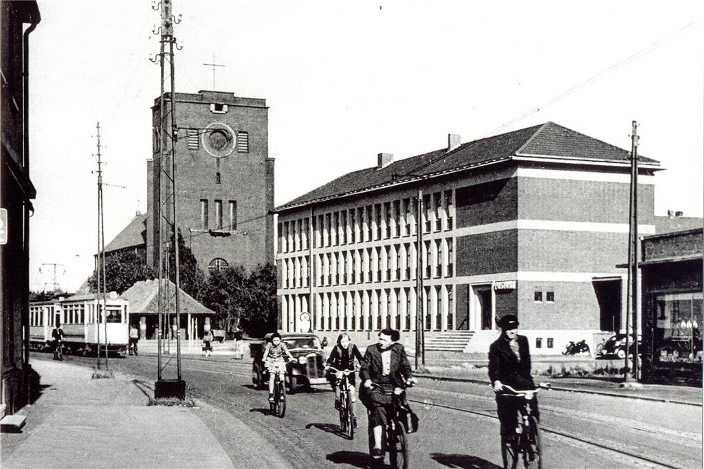 Die Straßenbahn vor dem Pavillon am Ickerner Marktplatz und der St.-Antonius-Kirche. Rechts im Bild ist das Verwaltungsgebäude zu sehen.