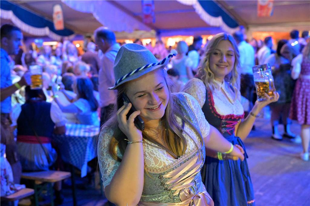 Eine Frau ist am Telefonieren, doch ihre Freundin möchte mit ihr auf die Tanzfläche