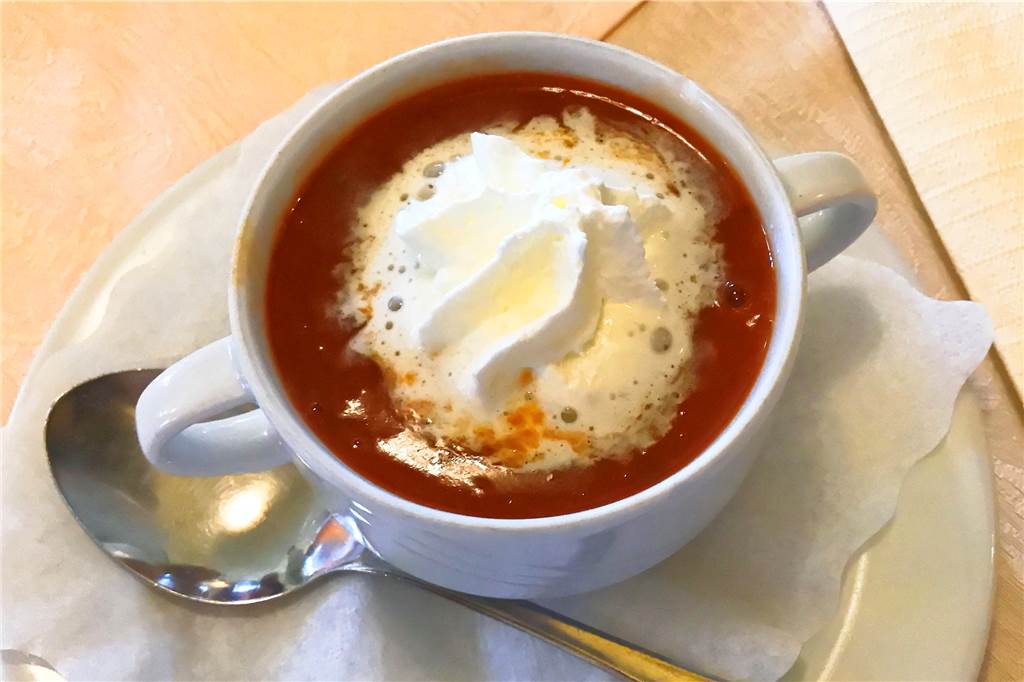 Die Tomatensuppe wird mit einer Sahnehaube serviert.
