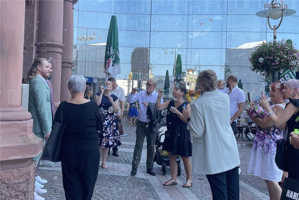 Outfit mit lustigem Detail: Marco und Patrick haben geheiratet Das Hochzeitspaar steht vor dem Standesamt. Seine Gäste pusten Seifenblasen in Richtung der beiden.