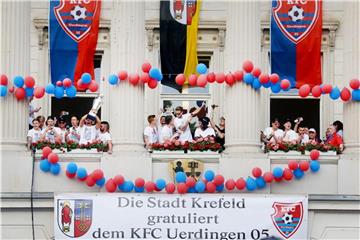 Die Uerdinger Mannschaft feiert mit dem Meisterpokal der Regionalliga West am Rathaus den Aufstieg in die 3. Liga. Foto: R. Weihrauch
