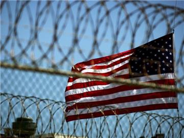 Die US-Flagge hinter einem Stacheldraht des Gefangenenlagers in Guantanamo-Bay auf Kuba. Foto: Mike Brown