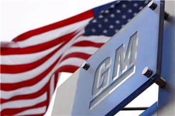 Die US-Flagge weht in Detroit hinter dem Logo des Automobilkonzerns General Motors. Foto: Jeff Kowalsky/epa