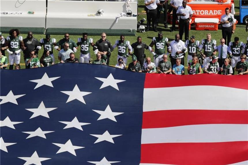 Die Verfplichtung der Sportler bei der Nationalhymne zu stehen erfüllen die Spieler der New York Jets, bilden aber als Zeichen des Protests eingehakt eine Kette. Foto: Frank Franklin II