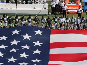 Die Verfplichtung der Sportler bei der Nationalhymne zu stehen erfüllen die Spieler der New York Jets, bilden aber als Zeichen des Protests eingehakt eine Kette. Foto: Frank Franklin II