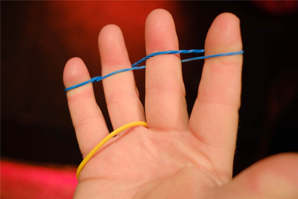 Zaubertrick zum Nachmachen: Salasas zeigt wie’s geht Ein Foto von Schritt eins des Zaubertricks zeigt eine Hand mit zwei Gummibändern.