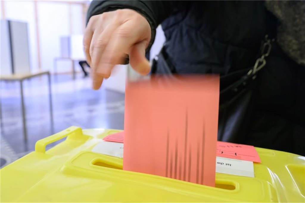 In diesen kuriosen Wahllokalen kann in NRW gewählt werden: ds Eine Frau wirft ihren Wahlzettel für die Bundestagswahl 2025 in der Briefwahlstelle im Neuen Rathaus in eine Urne.