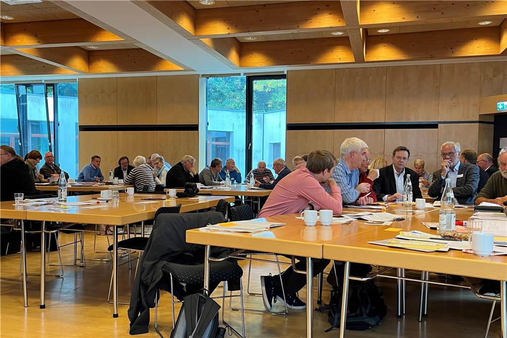 Soziale Projekte für angespannten Wohnungsmarkt: „Wir sind Vermittler“ Menschen sitzen an mehreren Tischen in einem Saal.