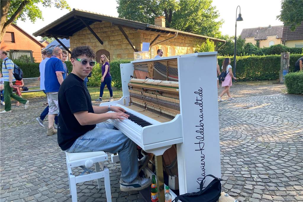 Mathias und Sohn Harald begeistert von ihrer ersten Extraschicht Ein junger Mann spielt auf einer Kopfsteinpflasterfläche am Schiffshebewerk Henrichenburg in Waltrop Klavier. Im Hintergrund sind einige Besucher der Veranstaltung Extraschicht zu erkennen.