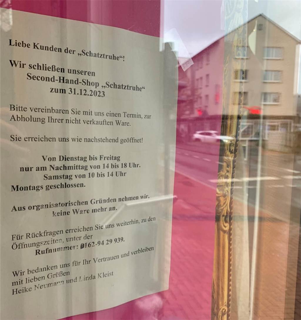 Ein Zettel hängt in der Tür des Geschäfts in der Altstadt. In der Spiegelung der Scheibe ist die Straße, ein Auto und ein Haus zu sehen.
