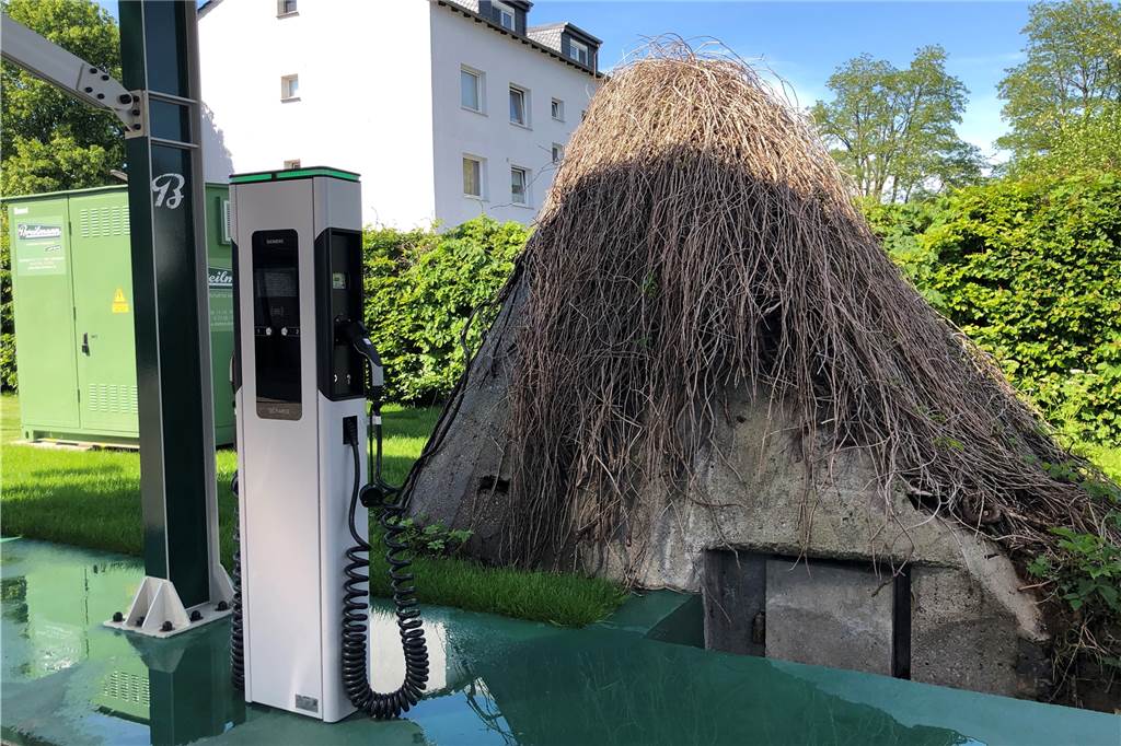 Bei Elektro Breilmann trifft Weltkriegs-Geschichte auf die Zukunft Direkt hinter den E-Ladesäulen fällt der Bunker aus dem Zweiten Weltkrieg auf.