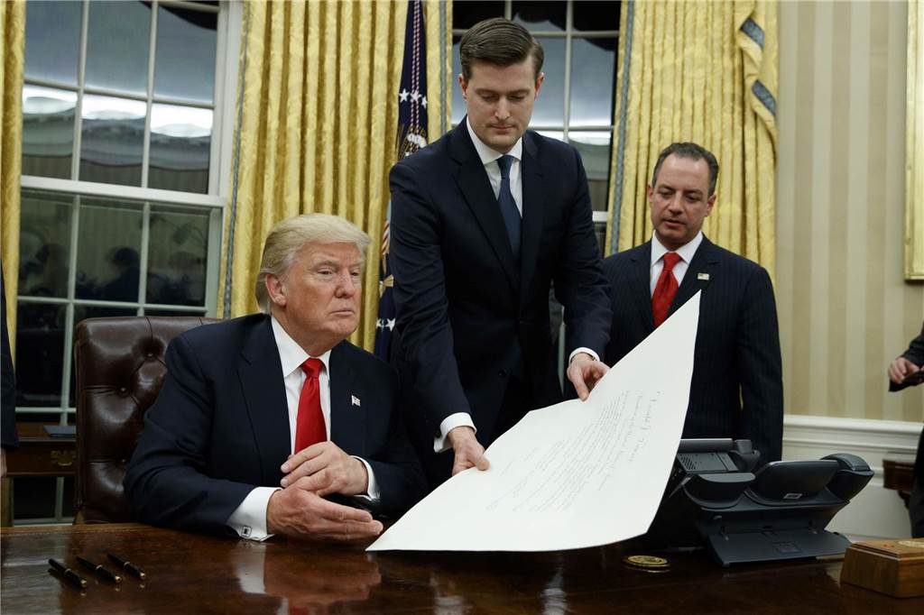 Donald Trump - Amtseinführung am Montag: So läuft der Tag des US-Präsidenten ab Staatssekretär Rob Porter (M) legt dem neuen US-Präsidenten Donald Trump (l) am 20.01.2017 nach der Amtsübernahme im Oval Office des Weißen Hauses in Washington (USA) die Ernennungsurkunde für den neuen Verteidigungsminister Mattis zur Unterzeichnung auf den Tisch - rechts Stabschef Reince Priebus.