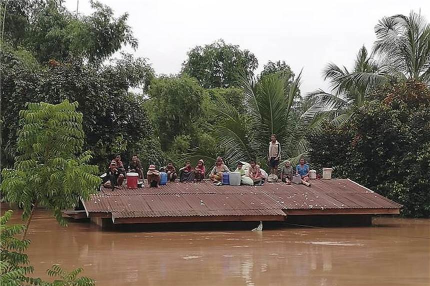 Dammbruch in Laos: Hunderte Menschen vermisst, mehrere Tote Dorfbewohner haben sich vor den Wassermassen aus dem eingestürzten Staudamm auf die Dächer eines Hauses gerettet. Foto: Attapeu Today/AP