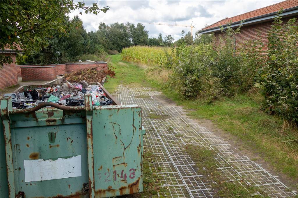 Neue Flüchtlingsunterkunft: Wichtiger Fortschritt bei der Bauplanung Ein Bauschuttcontainer steht auf einem Weg