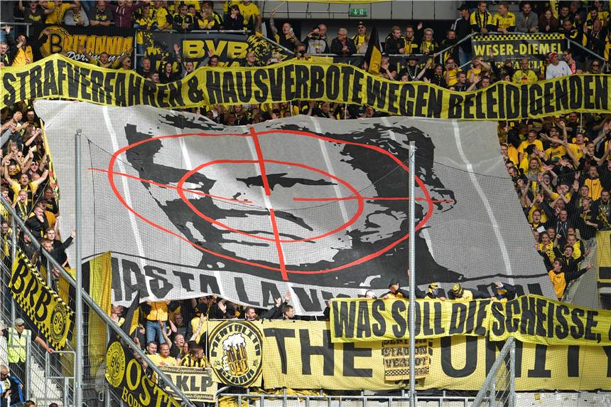 BVB ohne Fans nach Hoffenheim? Reaktionen zum Hopp-Urteil: „Dämlich“ oder „Domestizierung“ Dortmunder Fans halten ein Transparent mit dem Konterfei von Hoffenheims Mäzen Dietmar Hopp unter einem Fadenkreuz in die Höhe. (Archiv)