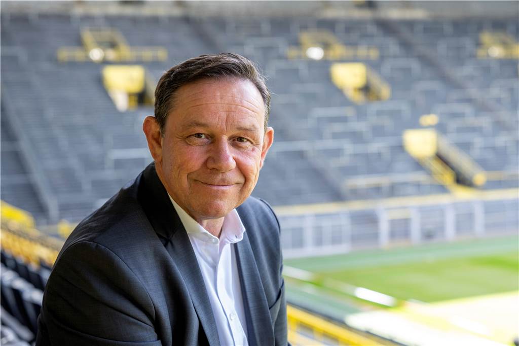 „Deutlich an Einfluss gewonnen“: So umfassend ist das BVB-Netzwerk in der Fußball-Welt Christian Hockenjos lächelt in die Kamera.