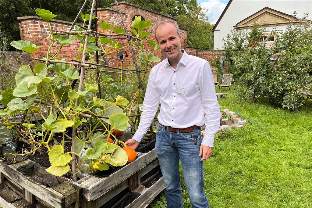 Dr. Johannes Michael Albers: „Bild von Psychiatrie ändert sich“ Dr. Johannes Michael Albers greift im Therapiegarten am Schloss Herten nach einem orangenen Kürbis.