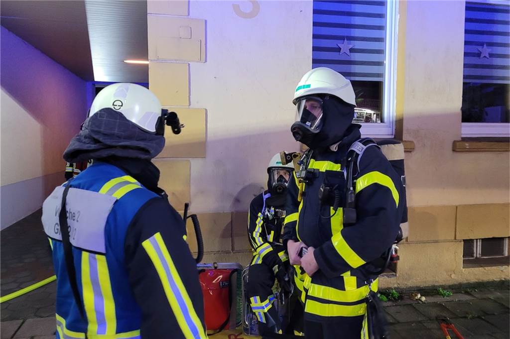 Haustiere sterben bei Wohnungsbrand in Bochum: Anwohnerin im Krankenhaus Drei Feuerwehrleute in ihren Schutzanzügen vor der Wohnung.