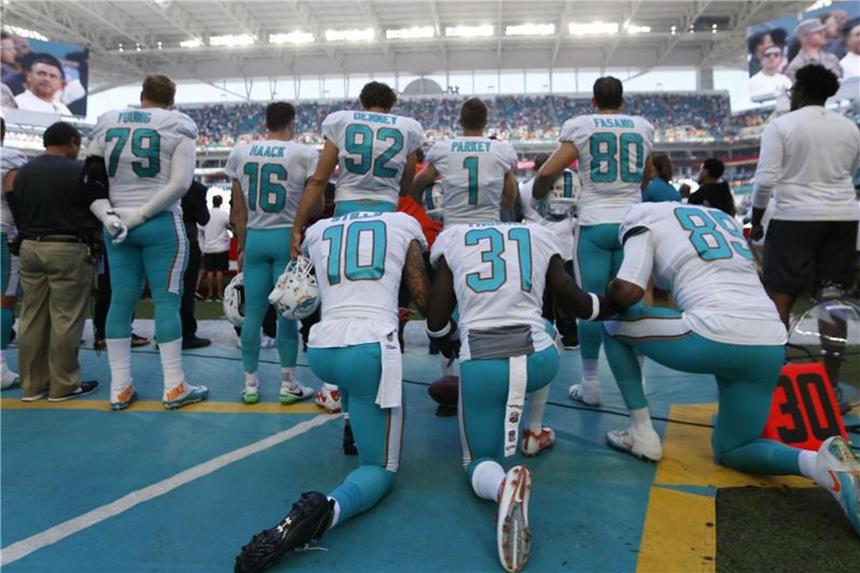 Miami bestraft Hymnen-Protest mit Spielsperren und Geldbußen Drei Spieler der Miami Dolphins (l-r) protestieren beim Abspielen der Nationalhymne. Foto: Wilfredo Lee/AP