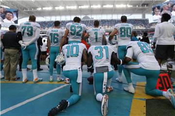 Drei Spieler der Miami Dolphins (l-r) protestieren beim Abspielen der Nationalhymne. Foto: Wilfredo Lee/AP