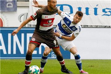 Duisburgs Fabian Schnellhardt (r) und St. Paulis Aziz Bouhaddouz kämpfen um den Ball. Foto: Roland Weihrauch