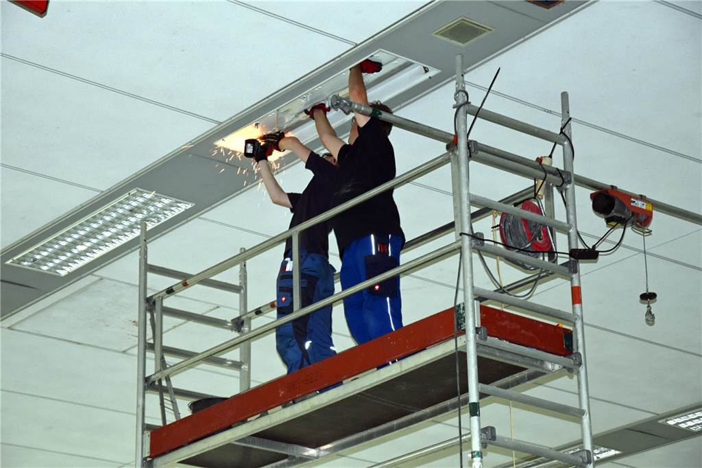 Hier entnehmen Mitarbeiter der Firma Elektro Steinkuhl alte Leuchtkörper aus einem Turnhallendach.