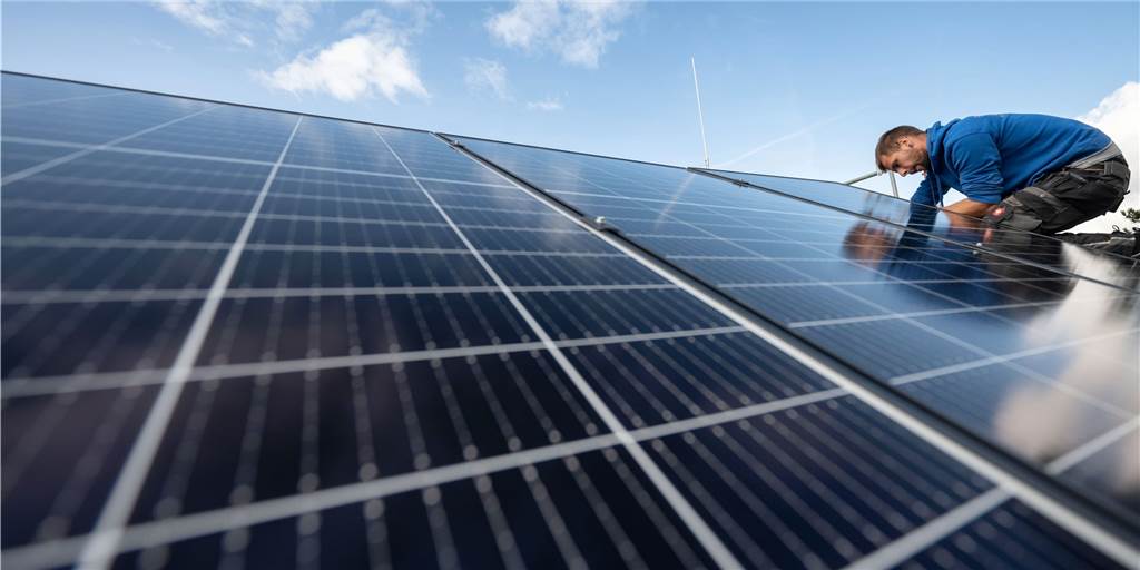 Fördergeld für Photovoltaik: Weitere Antragsteller haben Aussicht auf Mittel Ein Mann sitzt auf einem Dach mit PV-Anlage.