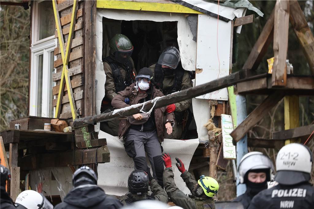Lützerath-Räumung bis tief in die Nacht: Aktivisten betonieren sich ein Ein Aktivist wird von Polizisten am zweiten Tag der Räumung im von Klimaaktivisten besetzten Braunkohleort Lützerath aus einer Holzhütte gehoben.